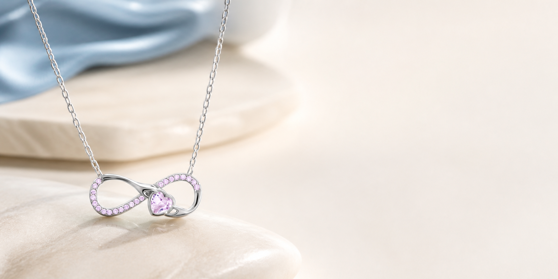 Infinity heart silver necklace on warm ivory with a mineral blue accent