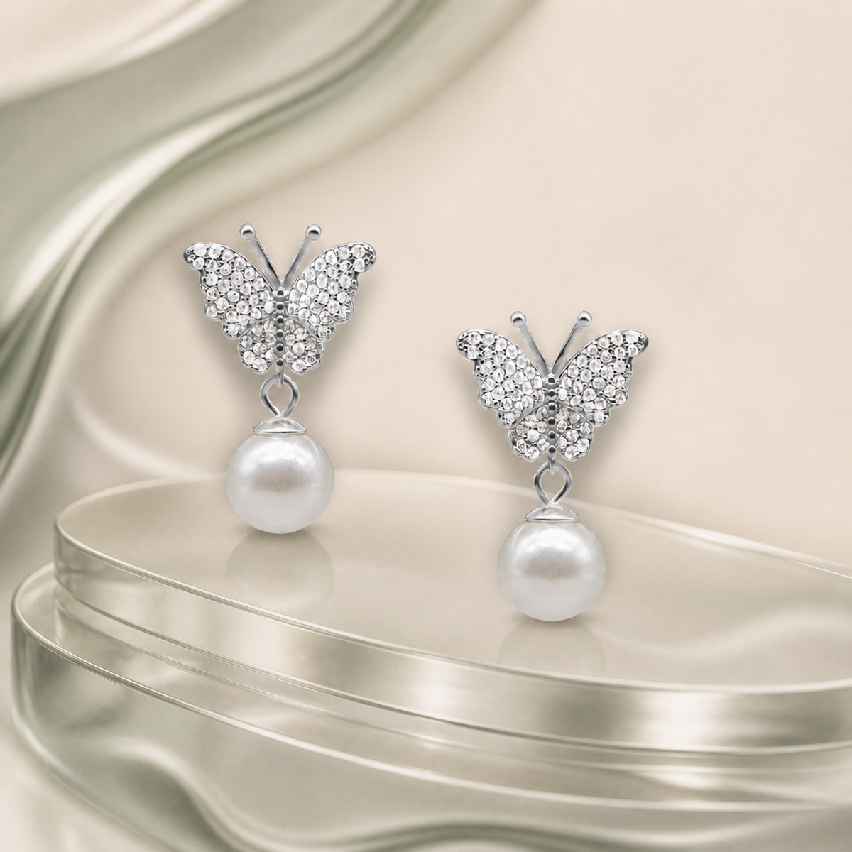 Butterfly pearl silver earrings on muted sage tinted glass