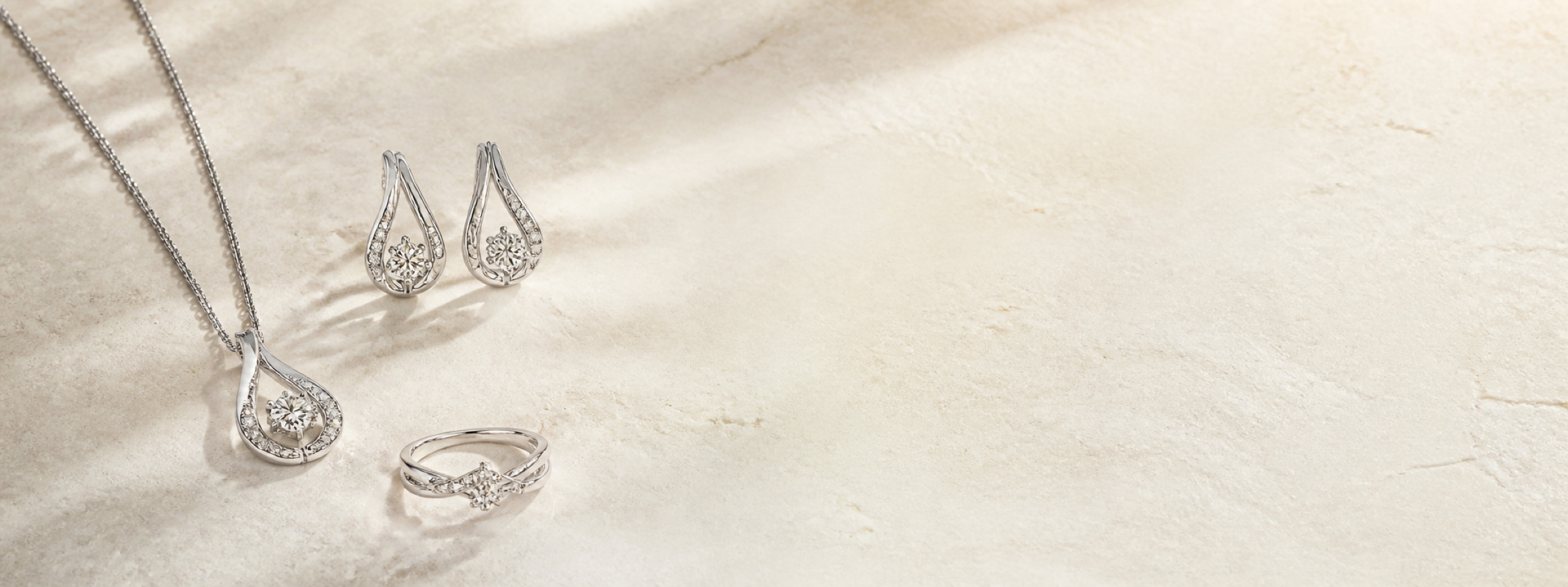 Silver jewellery arranged on a warm stone surface